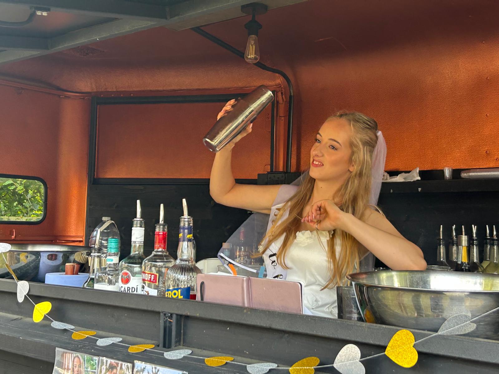 A bride shaking a cocktail behind the Away Days bar